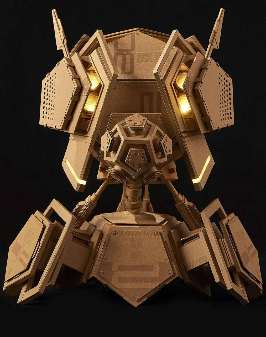 A layered cardboard construction by Greg Olijnyk with a circular centre and illuminated panels.