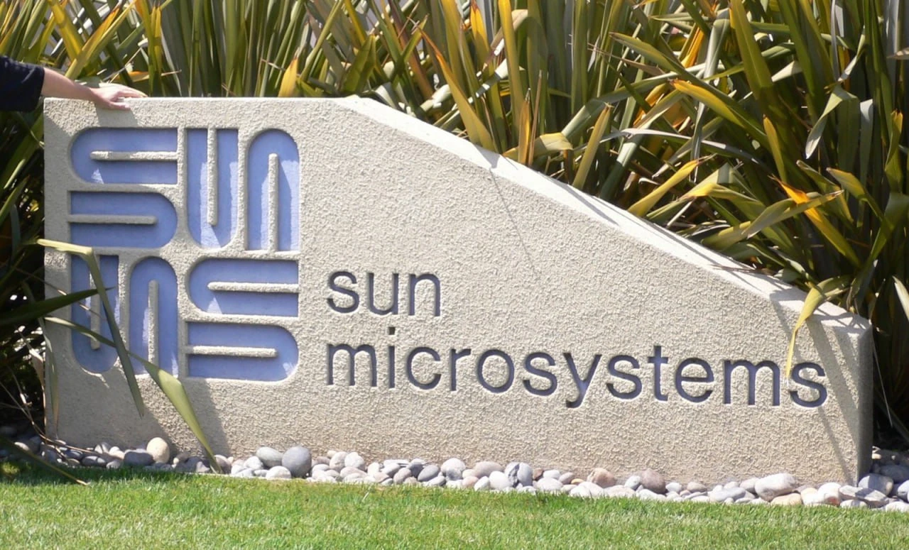 Кам’яна вивіска Sun Microsystems із квадратним знаком і назвою малими літерами серед зелених рослин.