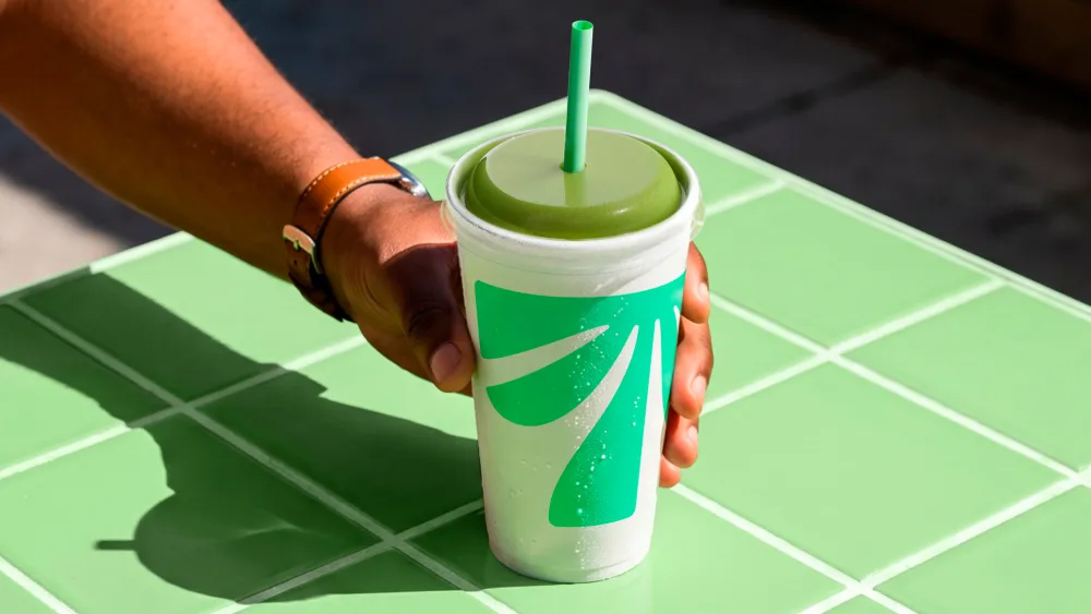 Tropical Smoothie Cafe cup with a large green palm, green lid and straw