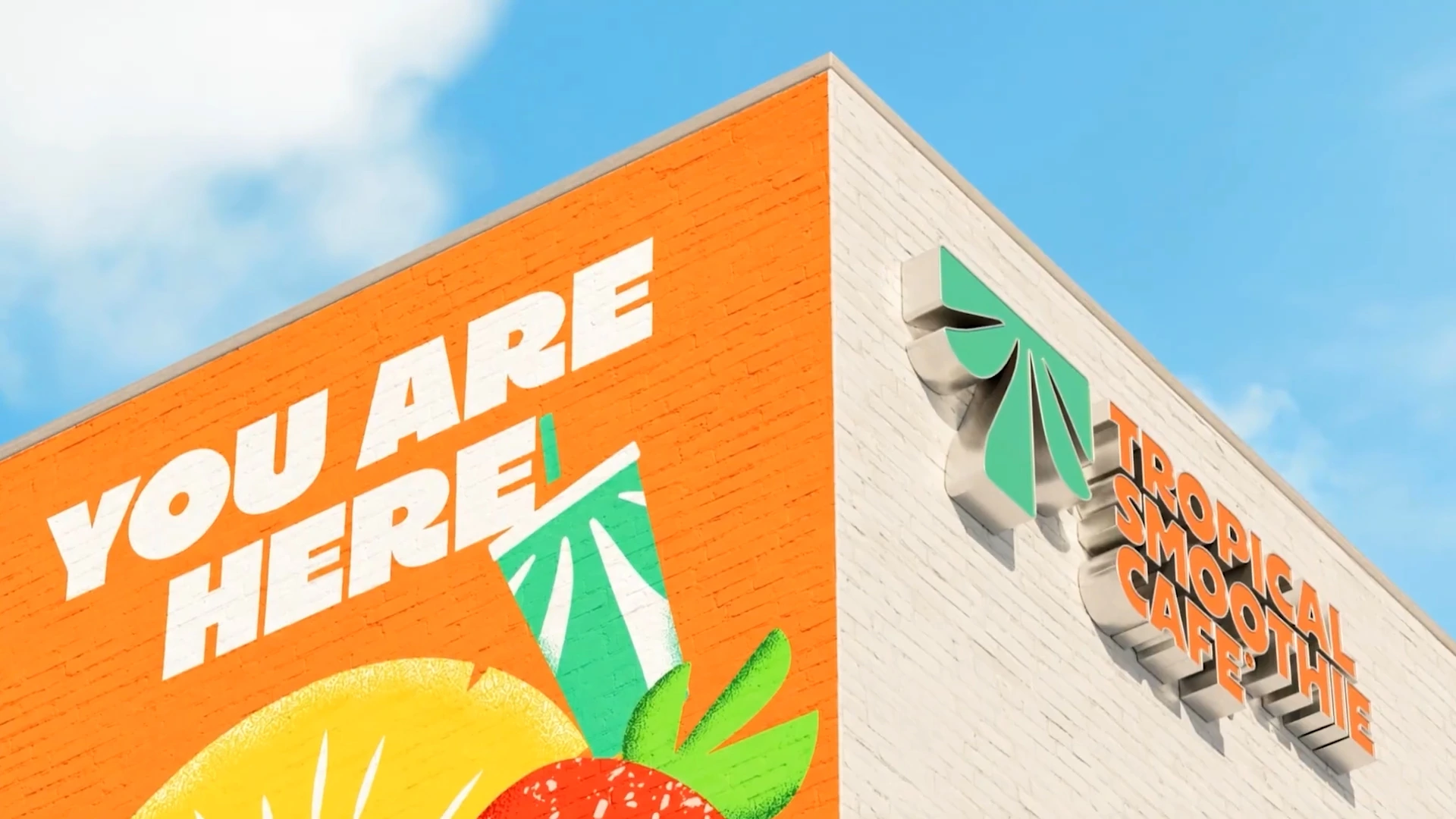 Building corner with Tropical Smoothie Cafe signage, an orange wall and the words You Are Here