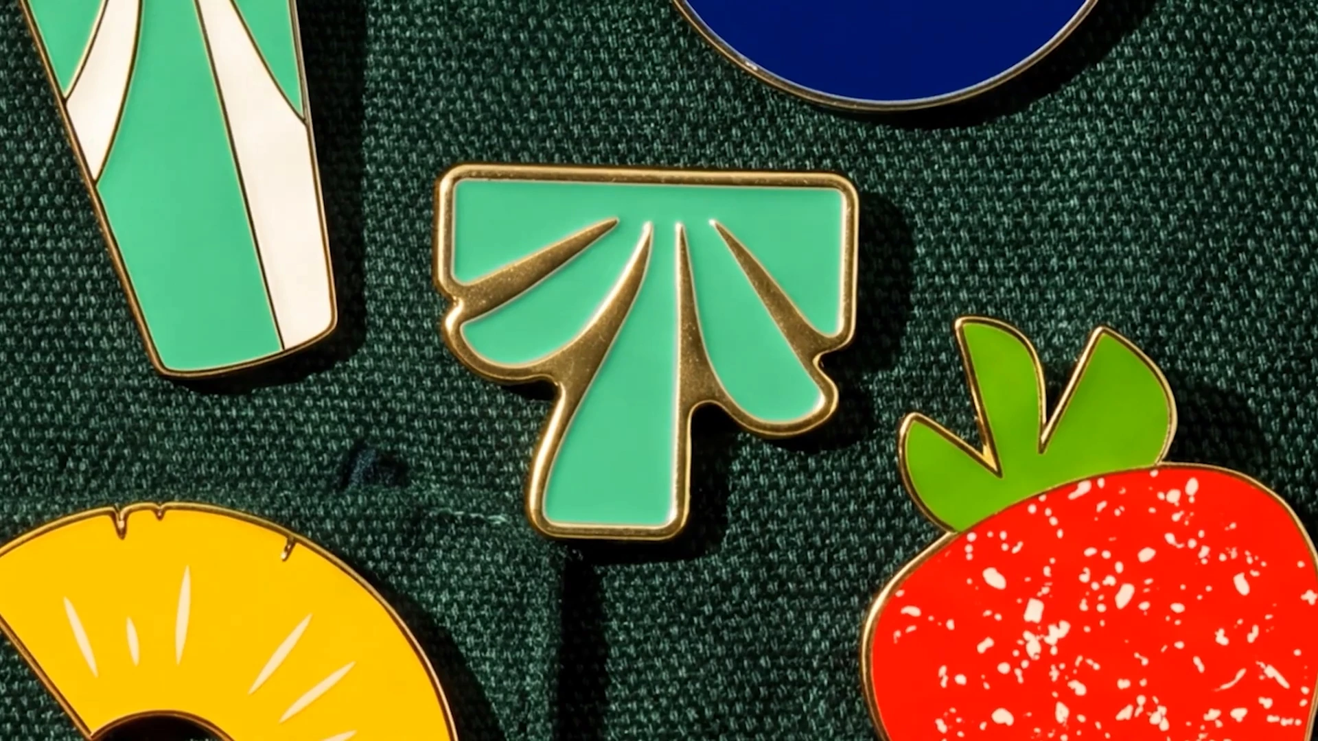 Green palm, strawberry and pineapple pins on dark green fabric