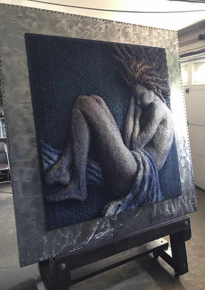 Bruce Mackley’s Descent: a seated female figure made of thousands of screws, surrounded by a wide metal frame.